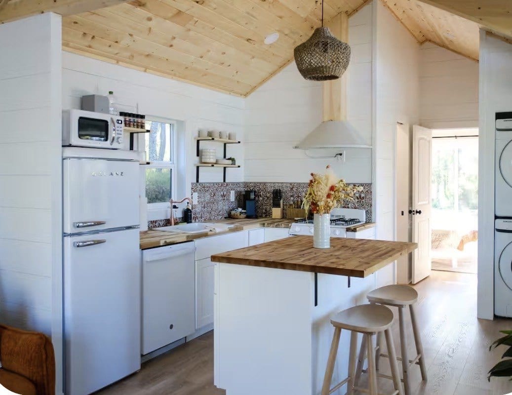 Finished Genesis Buildings interior with a vaulted pine ceiling, white shiplap walls, a retro fridge and a butcher-block kitchen island